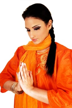 A beautiful east indian teen girl in her traditional silk dress and her long black hair standing for white background with folded hands praying.
