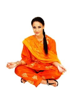 A gorgeous east indian teenager girl sitting on the floor with her legs crossed in the traditional indian dress for white background.