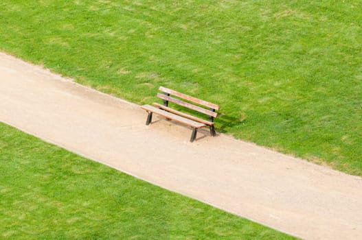lonely bench standing on park walk with green lawn by sides