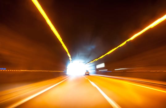 End of car tunnel with light and car on exit. Motion blur.