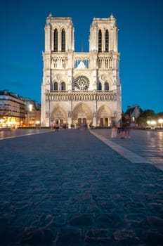 Notre Dame de Paris cathedral at night. Deep blue sky in background, copy space in foreground. Paris, France, Europe.