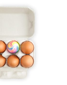 colorful painted easter egg in crate with ordinary eggs.  Isolated on white background. A lot of copy space.