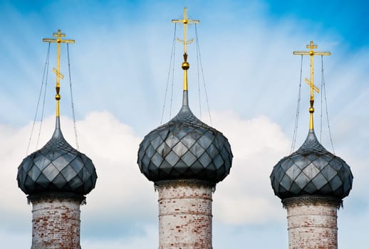 details of three church domes with  blue cloudy sky in background and sun rays. Rostov, Russia.