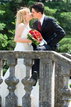 newly married couple kissing outside in the park