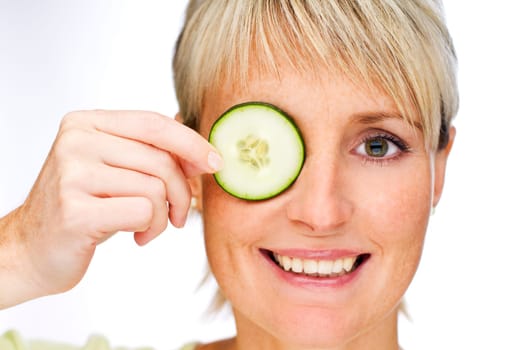 young blond woman holding cucumber on face close up
