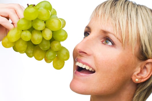 young blond woman eating green grape close up