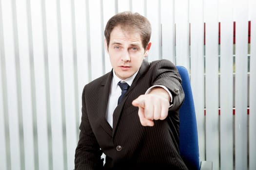 Businessman pointing a finger singling out a specific person to delegate work or to lay blame, indicating his choice or identifying somebody