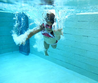 Happy little swimmer girl with bubbles in a swimming pool