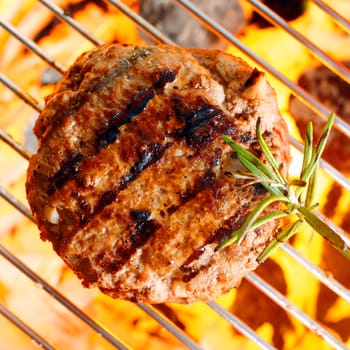 Hamburger patty on the grilling pan with open flames