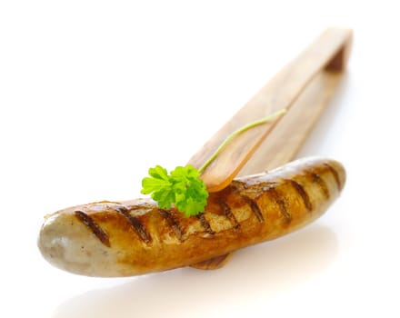 Grilled Bratwurst on the wooden tong isolated on