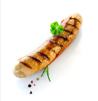 One cooked sausage with a sprig of parsley and rosemary shot against white.