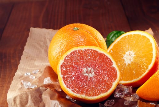 Halved fresh orange varieties with the traditional orange coloured pulp and the cara cara orange with its red-pink colouration on crumpled grungy brown paper