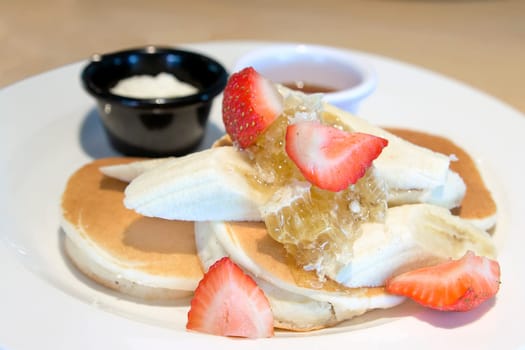 Pancakes with Bananas Strawberries Honeycomb Maple Syrup and Butter Closeup