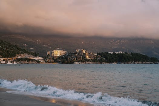 Reflections of a pink sunset on the sea coast at the foot of the mountains in the fog. High quality photo