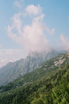 Fog over the peaks of a mountain range against a cloudy sky. High quality photo