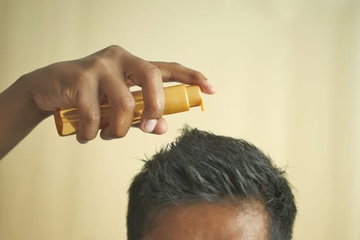 men applying oil on hair .