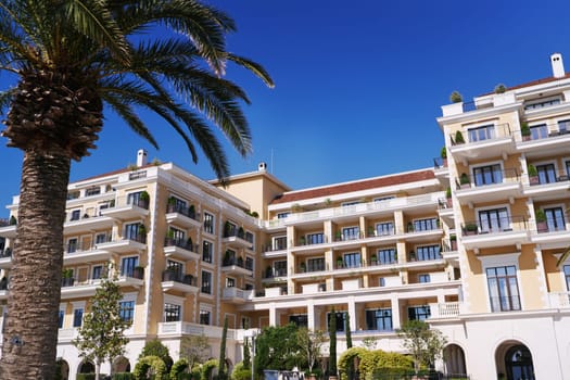 Hotel Regent with green palm trees against the blue sky. Porto, Montenegro. High quality photo