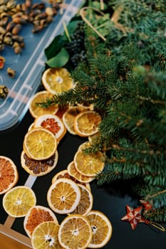 Dried pieces of orange, coniferous branches and acorns for a Christmas wreath lie on the table. High quality photo