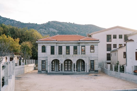 Old mansion with arcades and a red tiled roof against the backdrop of mountains. High quality photo