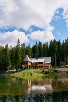 Wooden cottage on the shore of a lake on the edge of a coniferous forest. High quality photo