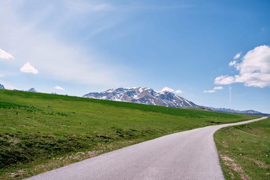 Highway in a green valley overlooking snow-capped mountains. High quality photo