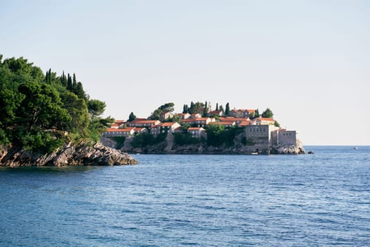 View from the sea to the island of Sveti Stefan behind the green cape. Montenegro. High quality photo
