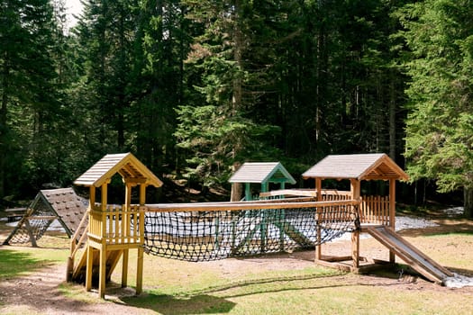 Wooden houses with agility bridge, climbing wall and slides in the forest. High quality photo