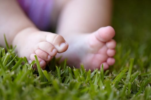 Feet, closeup and baby outdoor on grass, lawn and newborn toes on field in nature. Child, development or foot touching green, plants and close up of kid legs in garden with sensory experience.