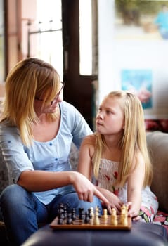 Talking, relax and a mother and child with chess for a game, teaching and thinking of a move. House, family and a mom, girl or kid learning to play a strategy competition for education and bonding.