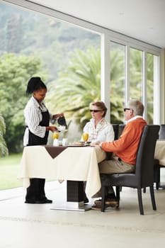 Waitress, coffee and senior couple in restaurant patio on romantic date together at table. Old man, woman and server with drink and breakfast service in luxury hospitality, hotel and relax on terrace.