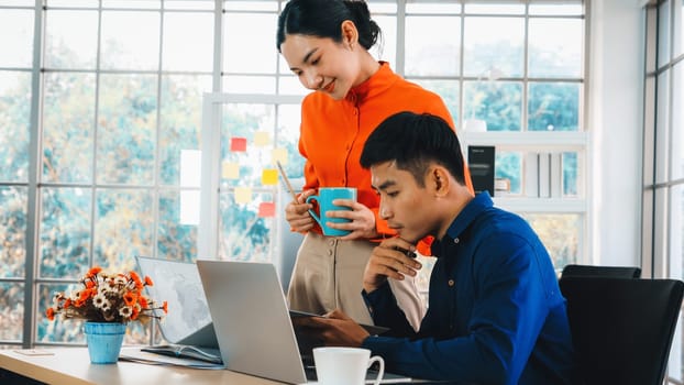 Two business people talk project strategy at office meeting room. Businessman discuss project planning with colleague at modern workplace while having conversation and advice on financial report. Jivy