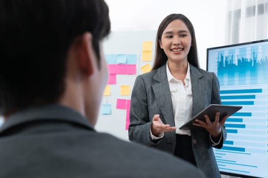 Young asian businesswoman presenting data analysis dashboard on TV screen in modern meeting. Business presentation with group of business people in conference room. Concord