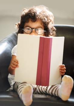 Child, portrait or glasses book read for fun education, learning or childhood development knowledge. Little girl, face on sofa for notebook studying or dress up as professional, school work or play.