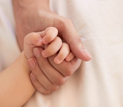 Parent, baby and holding hand for comfort on bed for love, trust or support in bond. Person, infant and caring with touch for child development, growth or health in wellness for quality time together.