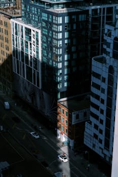 Aerial view of city streets with a blend of modern skyscrapers and traditional buildings, highlighted by sun rays amidst shadows. High quality photo