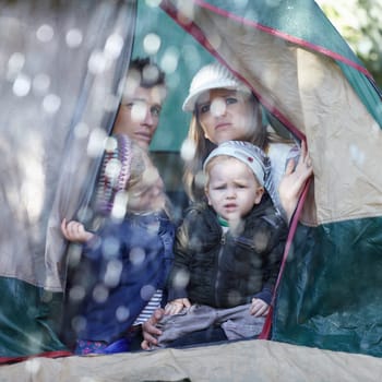 Camping, family and parents with children in rain sad for adventure, holiday and vacation in winter outdoors. Disappointed, unhappy and mother, father and kids in tent with bad weather for travel.