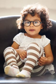 Toddler, girl and portrait or glasses for play, learning childhood development or education growth. Female person, kid or face eyewear on home relax sofa for intelligent, knowledge or nerd spectacles.
