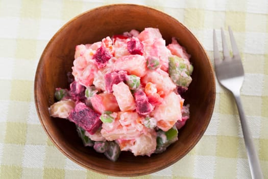Haitian potato salad in wooden bowl with fork.