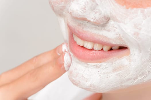 Smiling girl putting facial mask fingers cleaning treatment beauty
