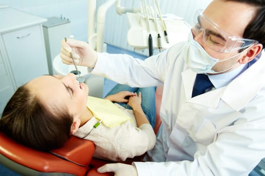 Smiling woman sitting in dentists chair while doctor examining her teeth