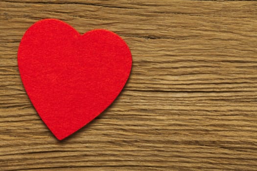 A large red felt heart on an old brown wooden board