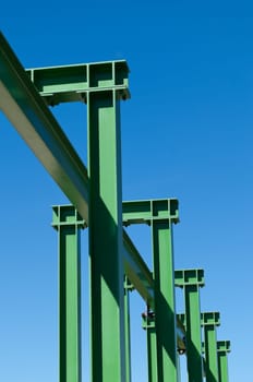 Detail of a small gantry crane painted green against the blue sky