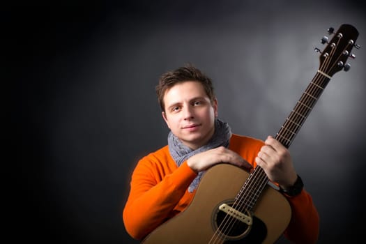 Calm man on background posing with acoustic guitar