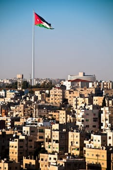 view of city of Amman with giant jordanian flag and blue sky in background