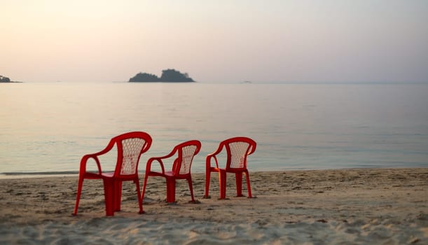 three red chair on an empty beach. sunset