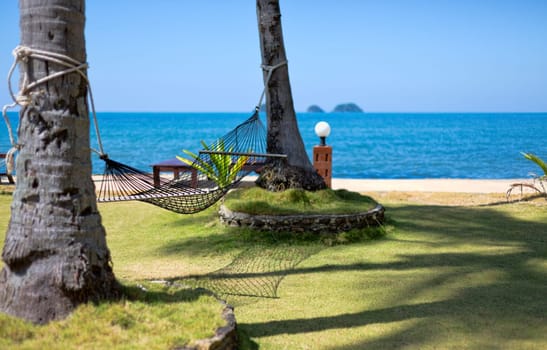 View of nice tropical empty sand beach with some palm and hammock . Koh Chang island. Thailand