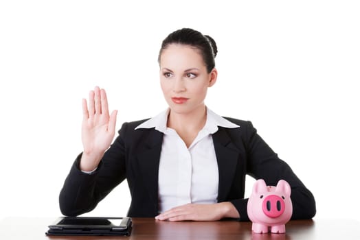 Businesswoman at the desk with tablet and piggy bank, isolated on white. Modern banking concept.