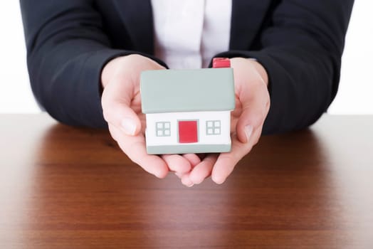 Businesswoman with house model over white - real estate loan concept
