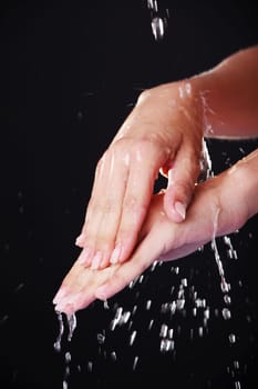 Water falling on female hands, over black background