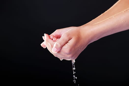 Water falling on female hands, over black background